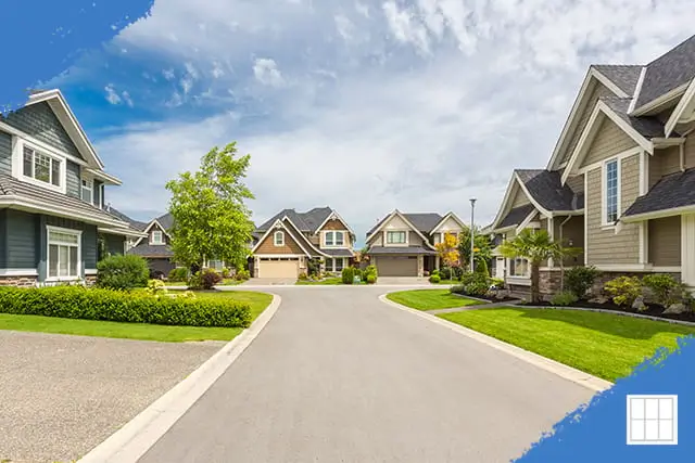 Wide-angle view of a peaceful suburban street in Kansas City with modern single-family homes and manicured lawns under a clear blue sky.