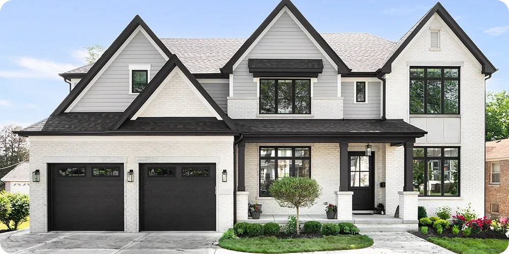 Modern Kansas City suburban home exterior with white brick and black garage doors, ready for new homeowners