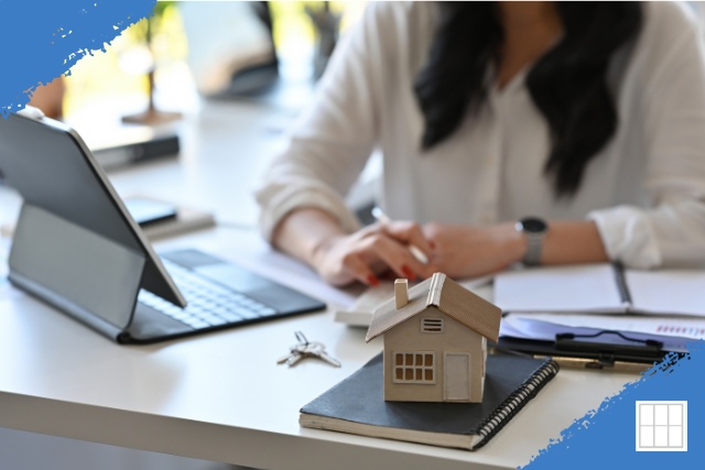 A financial professional or homeowner is reviewing documents next to a small model house and keys, symbolizing the analysis of home loan refinancing options.